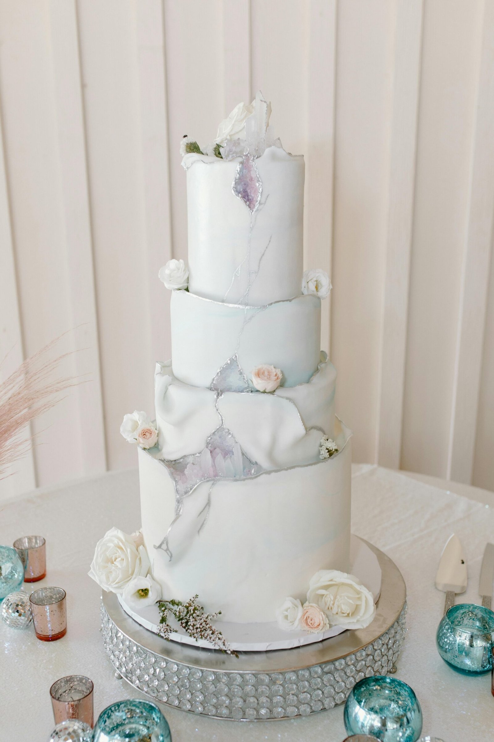 Four-tier white wedding cake adorned with delicate flowers and elegant design.